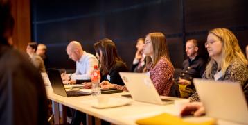 People sitting at a table with laptops in front of them